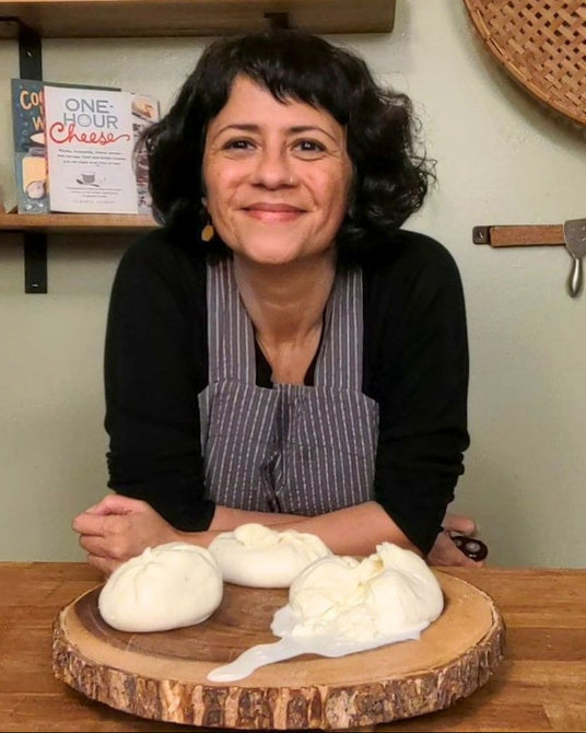 Woman in a kitchen with cheese on a wooden board