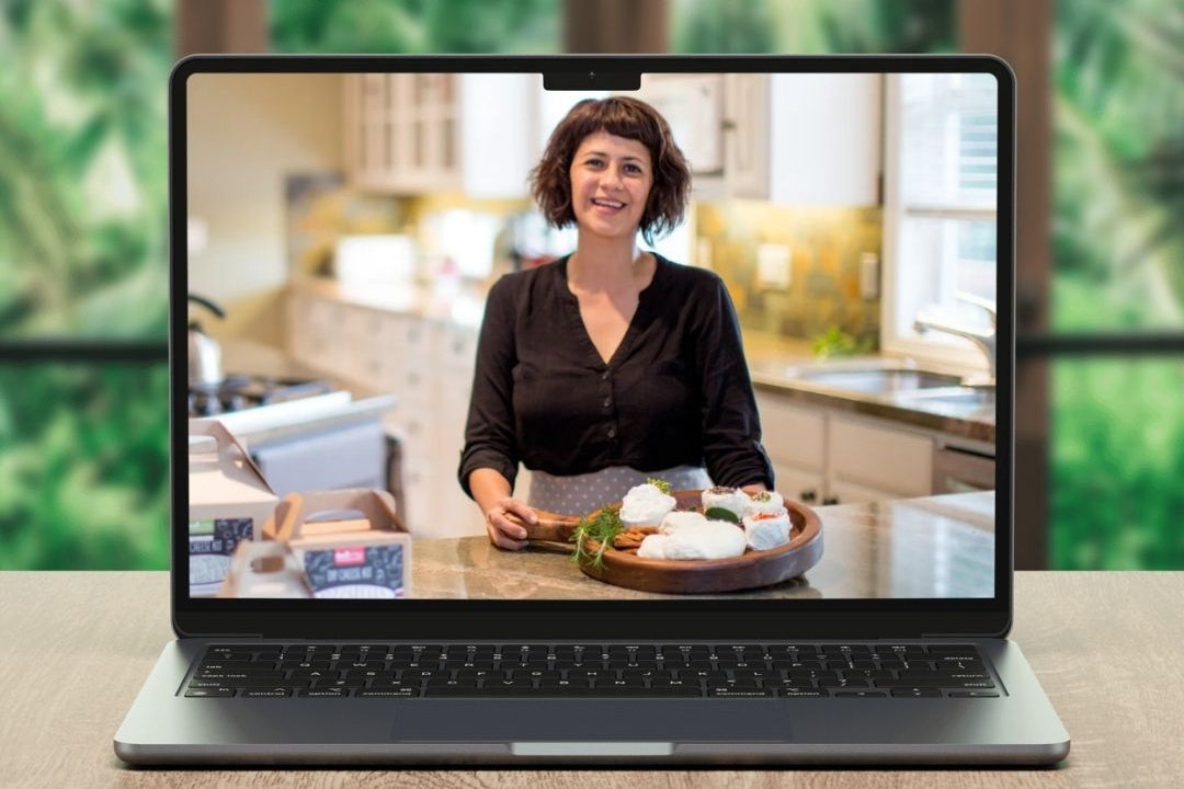 Laptop displaying a woman in a kitchen with a blurred green outdoor background