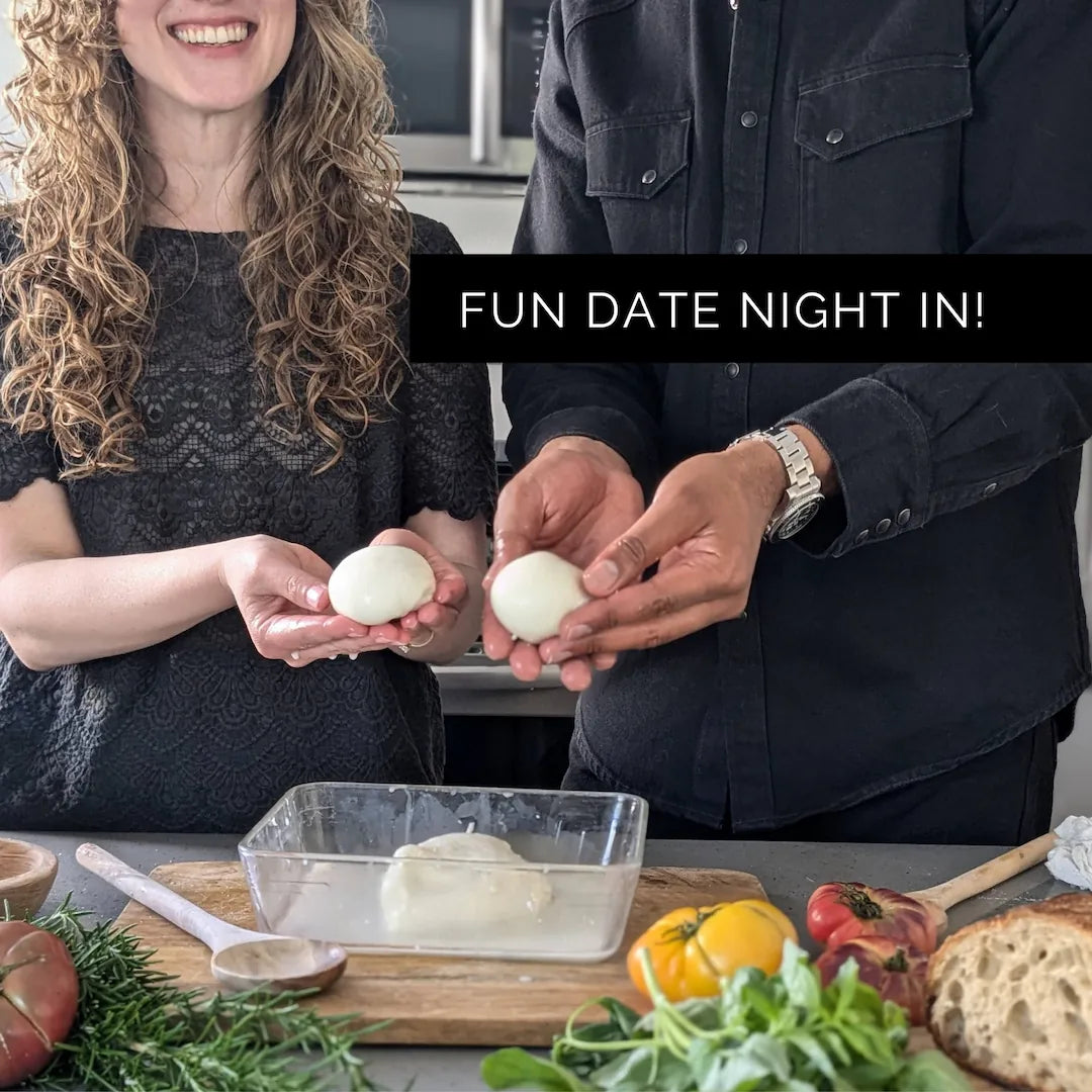 Two people holding their own homemade mozzarella balls with a text overlay 'FUN DATE NIGHT IN!' on a kitchen counter with food items.