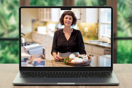 Laptop displaying a woman in a kitchen with a blurred green outdoor background