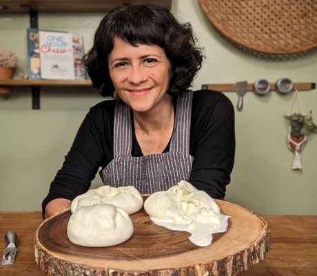 Woman in a kitchen with burrata on a wooden board