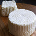 two wheels of fresh cheese on wood board 