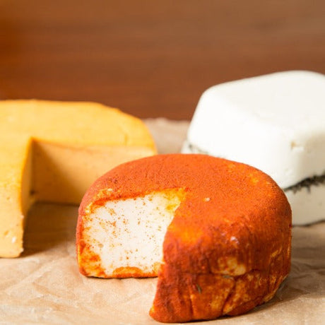 homemade vegan cheeses. one is a golden cheddar, one is covered in smoked paprika and one is a feta style with a line of herbs